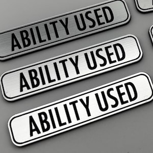 May include: Five silver rectangular labels with the text "ABILITY USED" printed in black.
