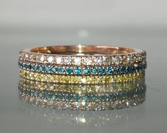 May include: A stack of four diamond eternity bands in rose gold. The bands are set with blue and yellow diamonds.