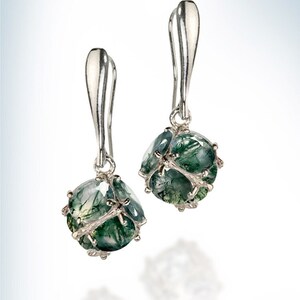 May include: A pair of silver dangle earrings with green agate stones. The stones are faceted and have a natural, organic look.
