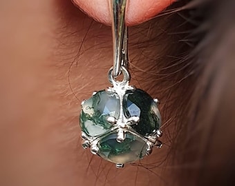 May include: Silver dangle earrings with a green moss agate stone.
