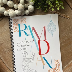 May include: A white and orange guide to a spiritual month with the word "RAMADAN" in large colorful letters. The guide features a black and white illustration of a person praying.