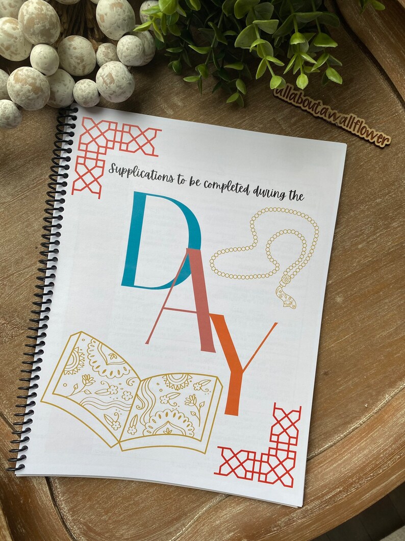 May include: A white spiral bound journal with the text "Supplications to be completed during the day" and the word "DAY" in large colorful letters. The journal has a red, orange, and gold geometric design on the cover.