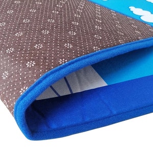 May include: Close-up of a blue and brown rug with a floral pattern. The rug has a blue border and a design of a blue sky with white clouds. The rug is made of a soft, durable material.