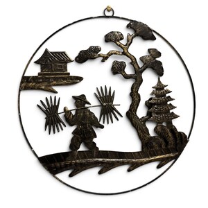May include: A circular black and gold metal wall art piece featuring a silhouette of a person carrying a pole with bundles across their shoulders, a small house, a pagoda, and a tree, all enclosed within a thin metal ring frame.