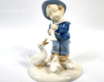 Porcelain figurine, boy playing flute with geese, gdr, mid century