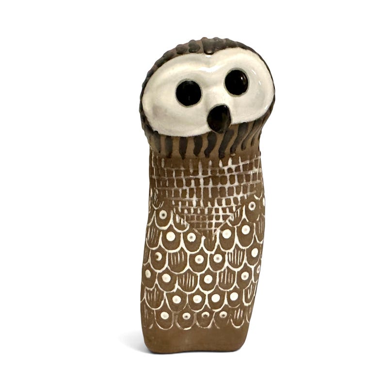 K&ouml;nnte beinhalten: Eine Eulenfigur aus Keramik mit einem glatten wei&szlig;en Gesicht, gro&szlig;en schwarzen runden Augen und einem kleinen schwarzen Schnabel. Der K&ouml;rper ist braun und mit einem strukturierten Muster aus wei&szlig;en Gitterlinien und wei&szlig;en Federn verziert.