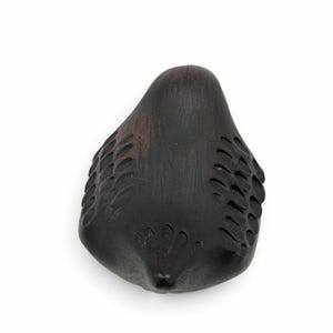 May include: A dark brown, carved wooden bird figurine with a smooth, rounded body and stylized, incised feather patterns along the wings and tail. The surface shows a deep, matte finish with subtle wood grain texture throughout the piece.