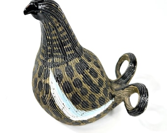 May include: A glass bird figurine featuring a black head and a textured body with a brown and black leopard-like spot pattern. The bird has a curved tail and a prominent white and light blue streak along its side, with a glossy finish.