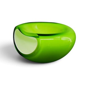 May include: A smooth, rounded glass bowl featuring a vibrant lime green exterior and a contrasting white interior. The bowl has a wide, open top and a distinct, curved indentation on one side, creating a unique, asymmetrical, and organic shape.
