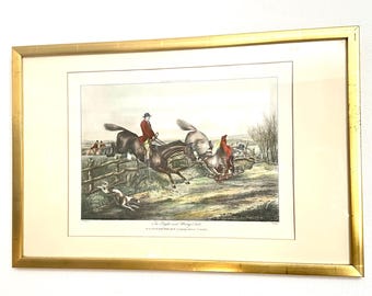 May include: A framed vintage-style print titled The Right and Wrong Sort, depicting a fox hunting scene with riders on horseback jumping over a wooden fence in a field. The artwork is enclosed in a thin, metallic gold-colored rectangular frame.