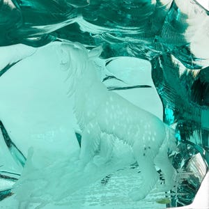 Peut inclure: Une sculpture en verre bleu sarcelle translucide pr&eacute;sentant un relief d&eacute;poli et grav&eacute; d'un f&eacute;lin sauvage debout sur une surface textur&eacute;e. Le f&eacute;lin est repr&eacute;sent&eacute; de profil, la t&ecirc;te tourn&eacute;e vers le haut, r&eacute;v&eacute;lant des d&eacute;tails de pelage.