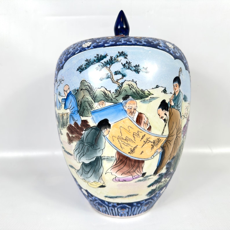 Puede incluir: Un tarro de jengibre de cer&aacute;mica con tapa que presenta una escena pintada a mano de figuras con t&uacute;nicas tradicionales examinando un pergamino. El tarro tiene un fondo azul claro con motivos de monta&ntilde;as y &aacute;rboles y un borde decorativo azul oscuro.