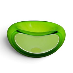 May include: A vibrant lime green glass bowl with a smooth, rounded, and asymmetrical shape. The bowl features a thick, translucent outer rim that transitions into a lighter, opaque interior basin, creating a layered effect with depth and clarity.
