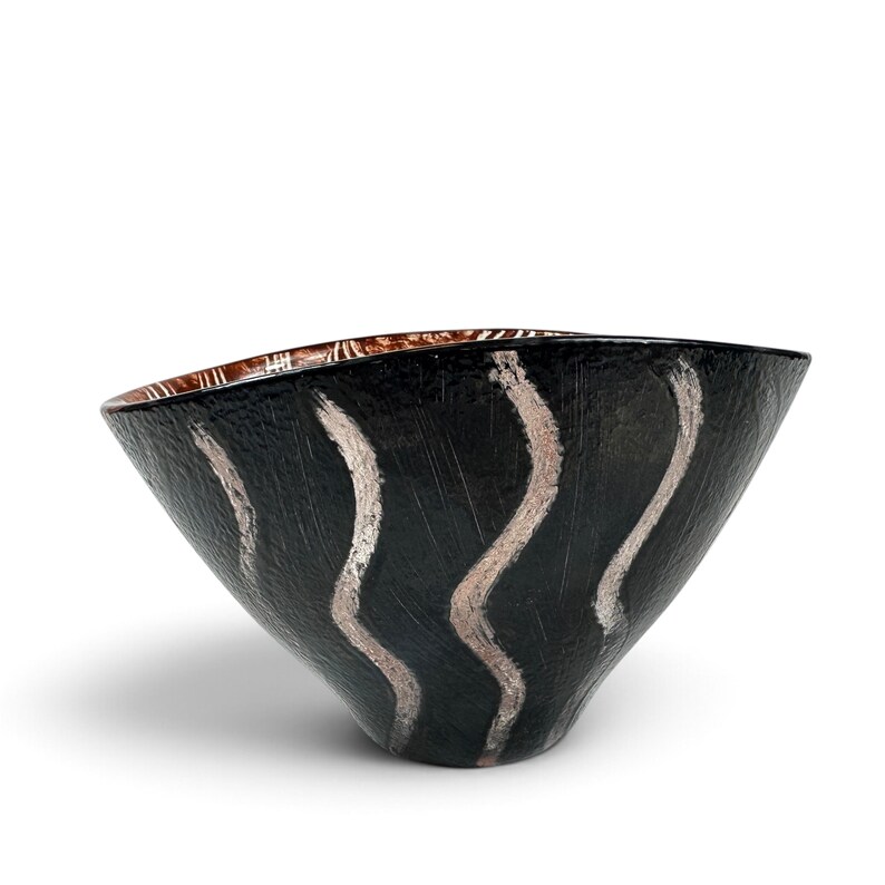 May include: A conical bowl with a textured black exterior featuring vertical, wavy silver brushstroke patterns. The interior of the bowl displays a contrasting metallic copper finish with visible linear markings along the upper rim.
