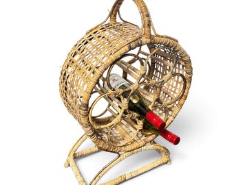 May include: A circular, woven rattan wine rack with a top handle and a stable base. The structure features multiple open compartments for bottle storage, with one glass wine bottle featuring a red foil cap inserted into the center opening.