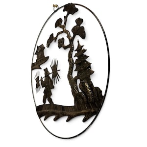 May include: A dark bronze-colored oval metal wall art piece featuring a cutout silhouette of a person carrying a pole with bundles, a tall tree, a multi-tiered pagoda structure, and a small building, all enclosed within a thin circular frame.