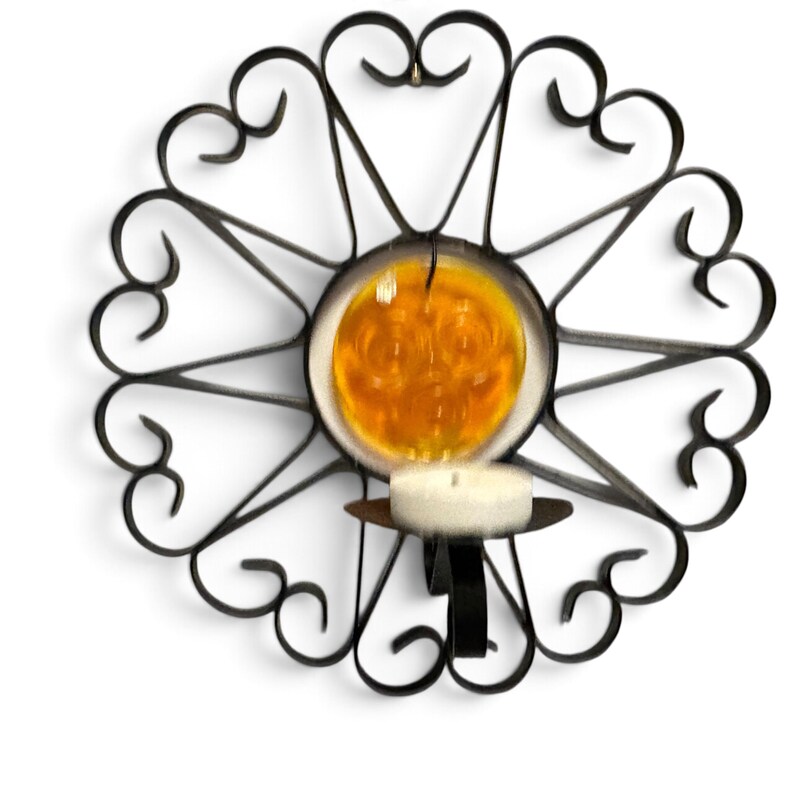 Peut inclure: Un bougeoir mural en m&eacute;tal noir compos&eacute; d'un cadre circulaire avec des volutes d&eacute;coratives et un disque en verre ambr&eacute; au centre. Une petite bougie chauffe-plat blanche est plac&eacute;e dans la coupelle en m&eacute;tal fix&eacute;e au bas du cadre.