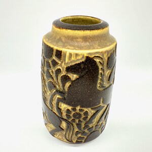 Peut inclure: Vase cylindrique en c&eacute;ramique marron fonc&eacute; et beige. Le vase pr&eacute;sente un motif en relief d&eacute;taill&eacute; de motifs floraux et animaliers stylis&eacute;s. Le bord et l'int&eacute;rieur sont de couleur beige clair. Environ 20 cm de hauteur.