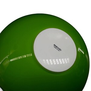 May include: A bright green bowl with a smooth, glossy finish. The underside features a circular white base centered on the bottom, which displays the black printed text "eva solo" followed by the smaller text "design by tools" underneath.