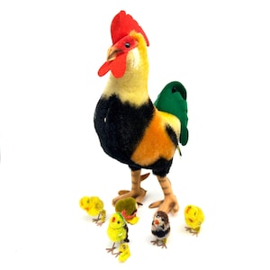 Puede incluir: Una colorida figura de gallo con cresta roja, cuerpo amarillo y negro y cola verde. Varias figuras pequeñas de pollitos amarillos y marrones se reúnen alrededor del gallo, creando un tema de animales de granja.