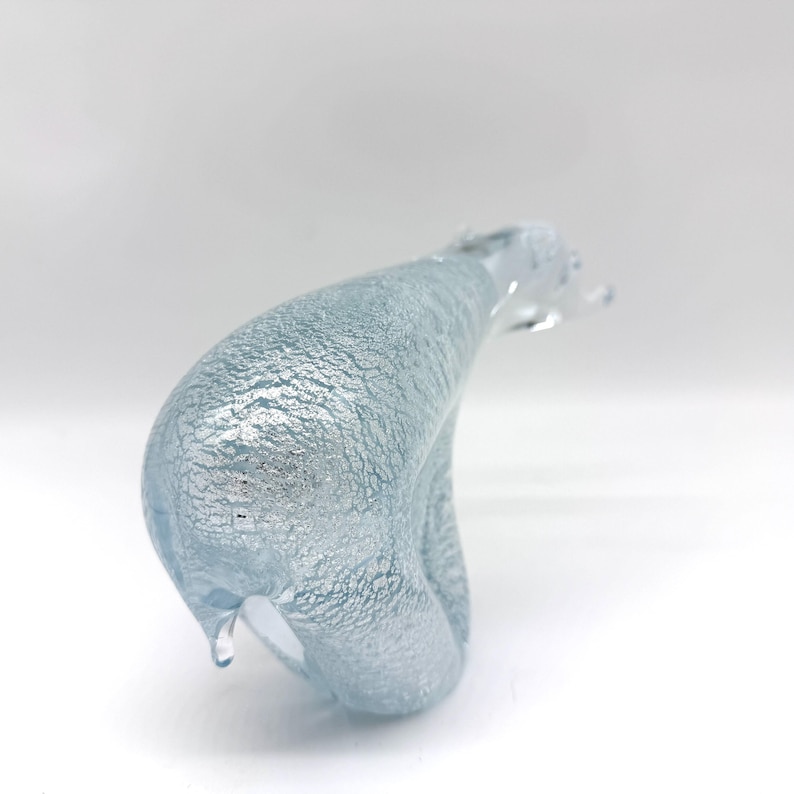 May include: A glass figurine shaped like a polar bear, featuring a translucent light blue body with an internal textured silver foil pattern that creates a shimmering, crackled effect throughout the entire surface of the sculpture.