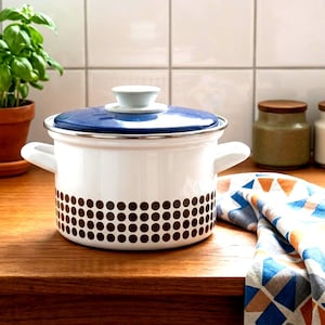 Peut inclure: Une casserole en émail blanc avec un couvercle bleu et des pois marron. La casserole a deux poignées blanches et un bouton blanc sur le couvercle. Un article de cuisine pour la cuisine.