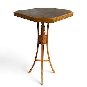 Peut inclure: Une table piédestal haute et élancée en bois, dotée d'un plateau octogonal à la finition brun foncé. La base est faite de bois clair moucheté avec trois pieds incurvés, un bloc central carré et un fuseau décoratif empilé.
