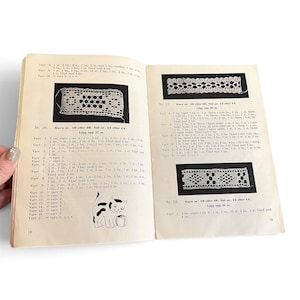 May include: An open instructional craft book with pages 18 and 19 visible. The pages contain black and white diagrams of lace patterns, Swedish text instructions for crochet, and a small illustration of a cat playing with a ball of yarn.