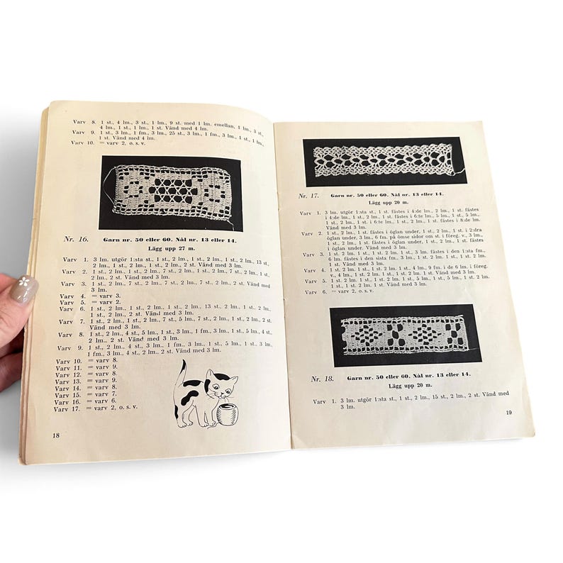 May include: An open instructional craft book with pages 18 and 19 visible. The pages contain black and white diagrams of lace patterns, Swedish text instructions for crochet, and a small illustration of a cat playing with a ball of yarn.