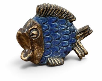 May include: A decorative fish figurine featuring a metallic gold head and tail with a textured blue body. The fish has a wide, open mouth, a prominent dorsal fin, and detailed scale patterns across its midsection, finished with a glossy glaze.