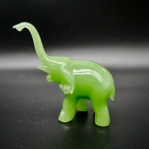 K&ouml;nnte beinhalten: Eine durchscheinende, hellgr&uuml;ne Elefantenfigur mit erhobenem R&uuml;ssel. Die Figur hat eine glatte, gl&auml;nzende Oberfl&auml;che. Der Elefant steht mit gro&szlig;en, detaillierten Ohren. Das Design ist schlicht und elegant.