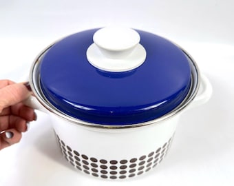 Op de afbeelding: Een wit en blauw geëmailleerde kookpot met een deksel. Het deksel is blauw met een witte knop. De pot heeft een witte body met een bruin stippenpatroon. De pot heeft twee witte handvatten en een zilveren rand.