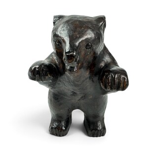 May include: A dark brown bear figurine with a glossy, textured finish. The bear is depicted in a standing position with its front paws extended forward, an open mouth showing teeth, and small, dark, rounded eyes set into the head.