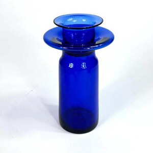 Op de afbeelding: Een kobaltblauwe glazen vaas met een brede, platte bovenkant en een cilindrische basis. De vaas is gemaakt van dik glas en heeft een gladde, gepolijste afwerking.