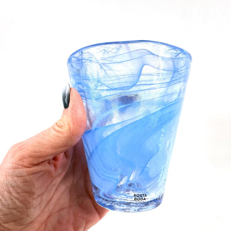 Puede incluir: Una taza de cer&aacute;mica blanca con asa negra y el texto "But First, Coffee" en negrita negra. La taza se encuentra sobre un fondo borroso, resaltando su dise&ntilde;o limpio.