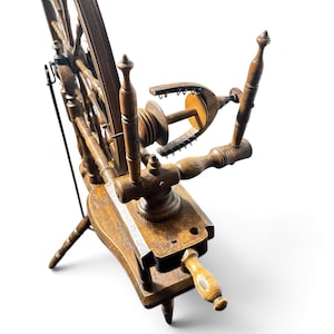 May include: A dark brown wooden spinning wheel featuring a large spoked drive wheel, a horizontal base, and a flyer assembly with a bobbin and metal hooks. The structure includes turned wooden supports and a tensioning screw mechanism.