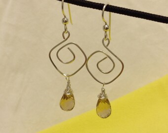 Peut inclure: Boucles d'oreilles en argent avec un motif en spirale et des pierres ambrées en forme de goutte.