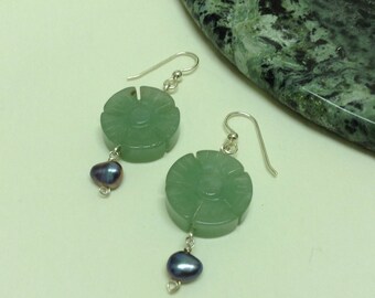 Peut inclure: Une paire de boucles d'oreilles pendantes en argent avec des pendentifs en forme de fleur de jade vert et des accents de perles noires.
