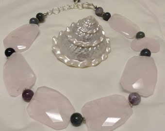 Peut inclure: Un collier de pierres précieuses rose et gris avec une chaîne en argent. Le collier présente de grandes pierres roses facettées et de plus petites pierres rondes grises et noires.