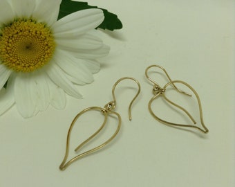 Peut inclure: Une paire de boucles d'oreilles dorées en forme de cœur. Les boucles d'oreilles sont faites de fil fin et ont un look simple et élégant.