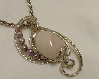 Peut inclure: Un collier en argent avec un pendentif en pierre rose et une chaîne de petites perles violettes.