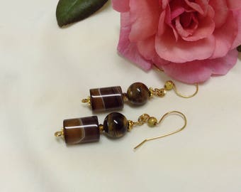 Peut inclure: Une paire de boucles d'oreilles pendantes dorées avec des perles d'agate brun et blanc et d'œil de tigre.