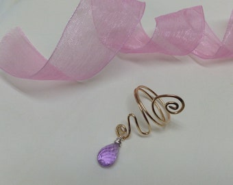 May include: A gold wire ear cuff with a dangling purple teardrop-shaped gemstone.