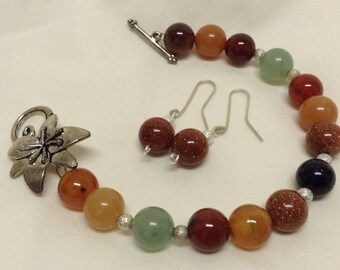 Peut inclure: Un ensemble de bracelet et boucles d'oreilles assorties, composé de perles multicolores. Le bracelet présente des perles aux tons terreux, notamment des nuances de marron, d'orange, de vert et de bleu. Les boucles d'oreilles ont de petites perles rondes et scintillantes.
