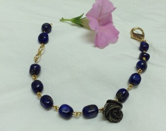 Peut inclure: Un bracelet en chaîne dorée avec des perles bleu foncé et un charme rose bleu foncé.