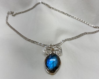 Peut inclure: Un collier en chaîne argent avec un pendentif en fil d'argent et d'or enveloppé mettant en valeur une pierre de labradorite bleue.