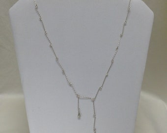 Peut inclure: Un collier en argent avec une chaîne délicate et de petites pierres claires. Le collier a un design en forme de Y avec deux brins de pierres qui pendent du centre.