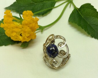 May include: A silver ring with a blue lapis lazuli stone set in a delicate wire design.