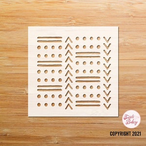 May include: White stencil with a geometric pattern of lines, dots, and triangles. The stencil is on a wooden background. COPYRIGHT 2021.