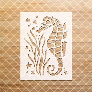 May include: White stencil of a seahorse with seaweed and stars. The seahorse is facing left and has a detailed design.